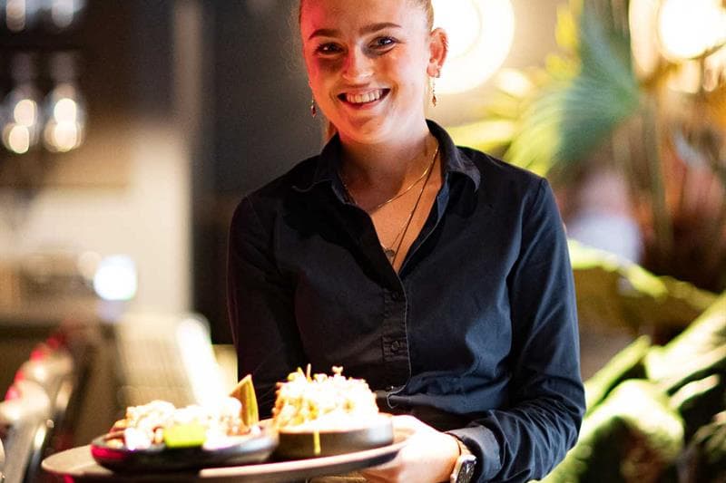 Female waitress carrying a tray of food